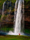 Landscape view of beautiful waterfall and person in red jacket, Iceland