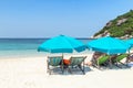 Landscape view of blue umbrellas with wooden beach chairs on tropical sandy beach in sunny day Royalty Free Stock Photo