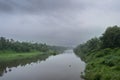 A landscape view of a calm river with green trees and mountain in India