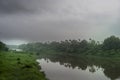 A landscape view of a calm river with green trees and mountain in India