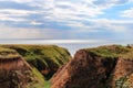 Landscape view clay cape mountains and cliffs near blue sea and skyline. Seascape of coast from green meadows. Clay rock in front