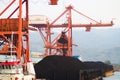 Landscape view of Coal-fired steam power station with gantry crane lifting coal stockpiles from ship cargo near Pelabuhan Ratu