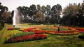 A landscape view of a garden where a gardener is watering the flowers.