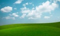 Landscape view of green grass on slope with blue sky and clouds background Royalty Free Stock Photo