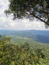 Landscape view of mountain range and cloudy blue sky with trees foreground, view from rainforest mountain peak of Gunung Panti