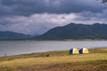Landscape view of nature Camping tents near river lake with mountain range and dramatic clouds sky background Royalty Free Stock Photo