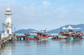 Landscape view of public white lighthouse on pier of Bang Bao fishing village with fishing boats mooring at Koh Chang Island,Trat,