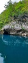 Landscape view of a small entrance of a mountain cave over the edge of a lake Royalty Free Stock Photo