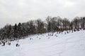 Landscape view of a snowy hill with families with children sledging and having fun in snow, Cmrok in Zagreb