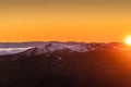 Landscape view with snowy and rocky mountain at sunset, fiery sky and sun background