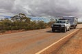 Landscape view of 4WD and modern caravan on an outback highway in Australia under a blue cloudy sky