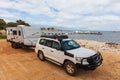 Landscape view of a 4WD and modern caravan parked next to a seaside jetty