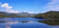 Landscape view of white cloud, blue sky and green mountain background with reflection on lake or river at Huai Bon reservoir Royalty Free Stock Photo