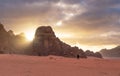Landscape of Wadi Rum desert in sunrise with a man walking alone, and sunlight through stone mountain. Travelling and adventurous