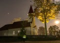 Landscape with white church in the moonlight, illuminated tree in autumn colors at night Royalty Free Stock Photo