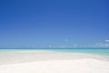 Landscape of a white sandy beach leading into turquoise waters under a blue sky on the island of Fakarava in French Polynesia