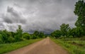 Landscape with a wide forest road and a sky with storm clouds Royalty Free Stock Photo