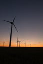 A landscape with windmills in a wind farm at sunset generating alternative and green energy source Royalty Free Stock Photo