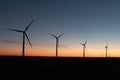 A landscape with windmills in a wind farm at sunset generating alternative and green energy source Royalty Free Stock Photo