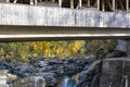 Landscape with a wooden bridge with flower baskets thrown over a rocky ravine with a mountain stream and autumn colorful maples on Royalty Free Stock Photo