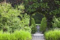 Landscaped garden with hedge arch opening to pond with a fountain statue . Royalty Free Stock Photo