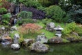 A landscaped Japanese garden with a waterfall and various trees, shrubs, grasses, ferns and a stone lantern Royalty Free Stock Photo
