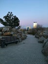 Landscaped park with decorative wild stones. Modern skyscrapers. Evening city.