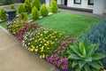 A landscaped small front yard with different plants and synthetic turf.