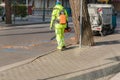 Landscaper worker cleaning foot way in park from dead leaves. Using electric powered Leaf Blower