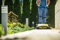 Landscaper Worker with Push Sweeper Cleaning Garden Pathway