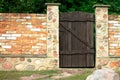 Landscaping. Red brick fence with brown wooden gate in the courtyard of private house. Stone path Royalty Free Stock Photo