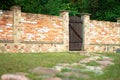 Landscaping. Red brick fence with brown wooden gate in the courtyard of private house. Stone path Royalty Free Stock Photo