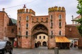 Restored medieval town gate Landtor in old town. Old red brick gate and people walking along streets on rainy summer day