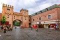 Restored medieval town gate Landtor in old town. Old red brick gate and people walking along streets on rainy summer day