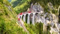 Landwasser Viaduct in Filisur, Switzerland. It is landmark of Swiss Alps. Red train of Bernina Express on high bridge in mountains Royalty Free Stock Photo