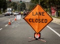 Lane Closed orange diamond shaped sign with work crew in distance Royalty Free Stock Photo
