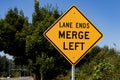 Lane ends merge left sign with trees Royalty Free Stock Photo