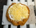 Langos - Hungarian street food, deep fried flatbread topped with sour cream, grated cheese on top of a white bench