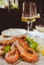 Langoustine with lemon and wine. Seafood close up. Fish dish with glass of wine. Fish restaurant menu. Grilled scampi with salad.