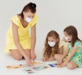 Language and foreign language learning. An English teacher conducts a masked lesson to two masked girls. Royalty Free Stock Photo