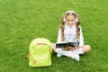Language learning course. Girl child learn English sitting on green grass. Foreign language. Audio lesson Royalty Free Stock Photo