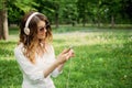 Language Learning, online study concept. Young girl in headphones and with a smartphone learns a foreign language in the park