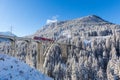 Red Rhaetian railway train on viaduct Langwies, sunshine, winter Royalty Free Stock Photo