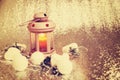 Lantern with burning candle surrounded by Christmas-tree decorations Royalty Free Stock Photo