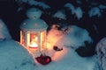 Lantern with a burning candle under a snow-covered Christmas tree in the courtyard of the house in the snowdrifts Royalty Free Stock Photo