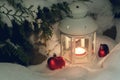 Lantern with a burning candle under a snow-covered Christmas tree in the courtyard of the house in the snowdrifts Royalty Free Stock Photo