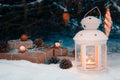 Lantern with a burning candle and wrapped gifts in the snow under the Christmas tree on Christmas Eve Royalty Free Stock Photo
