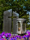 A lantern in front of a Christian tombstone