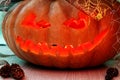 A lantern with a pumpkin head for Halloween, with a candle inside, a dark frightening smile with fangs.