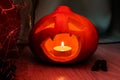 A lantern with a pumpkin head for Halloween, with a candle inside, a low key, a gloomy frightening smile with fangs.